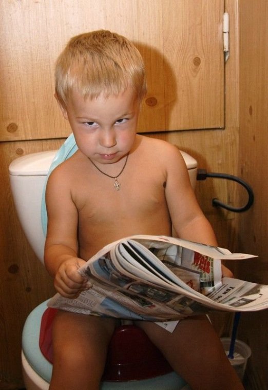Мальчик в туалете читает газету.