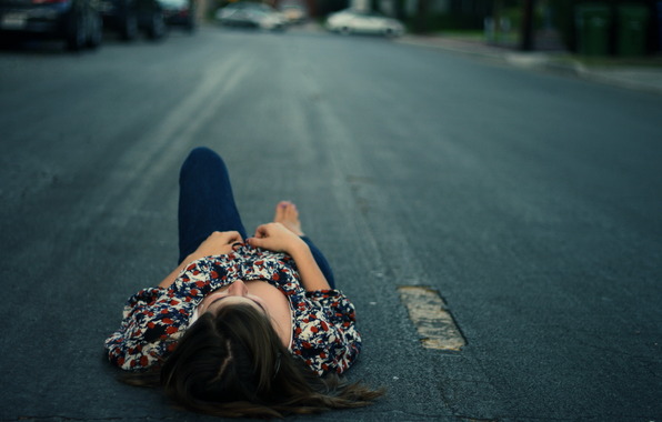 Девушка лежит на дороге.