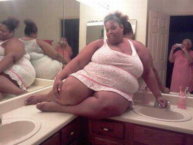 Толстая девушка фотографируется в ванной.