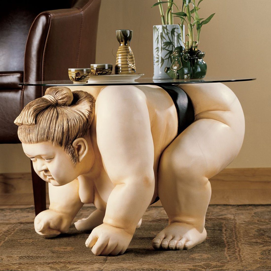 Стеклянный столики у которого ножкой служит статую борца сумо.