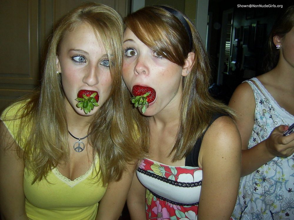 Две девушки засунули себе в рот клубнику.