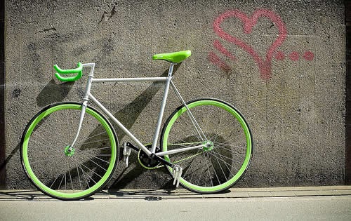 Салатовый велосипед на фоне старой стены.
